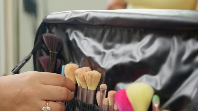 Professional makeup artist selecting a brush from a tool kit