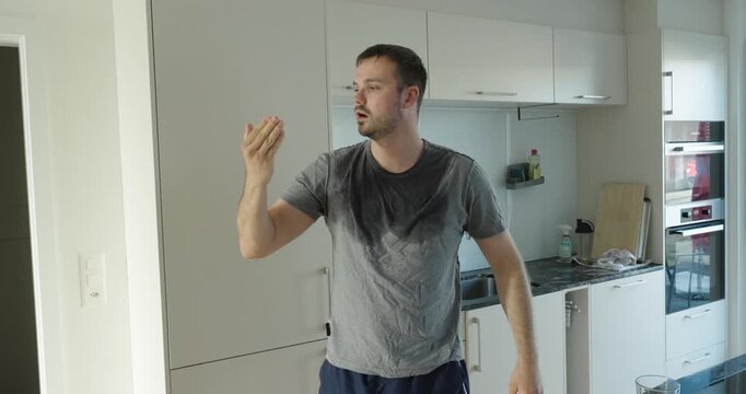 Man sweating heavily inside a hot kitchen during a heatwave, showing summer heat, exhaustion and uncomfortable indoor temperatures.