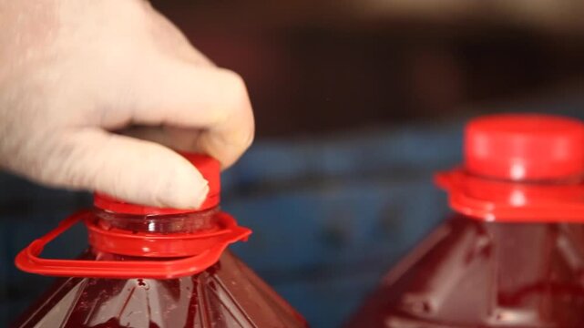Worker putting a red cap on a bottle of traditional turnip juice or fruit juice in a local facility.