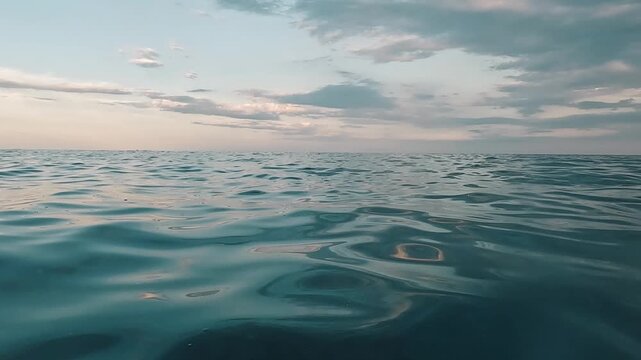 V&iacute;deo de mar abierto grabado a ras de agua, con oleaje suave, horizonte amplio y cielo parcialmente nublado con luz c&aacute;lida. La escena muestra una atm&oacute;sfera tranquila y cinematogr&aacute;fica, &uacute;til para conce