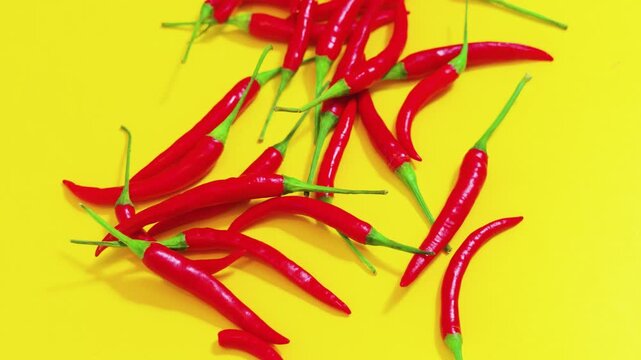 Fresh red bird's eye chili peppers on yellow background