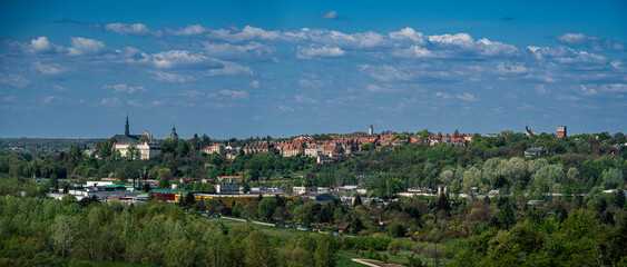 Obraz premium Panoramic view of a European town with historic buildings and greenery under a blue sky
