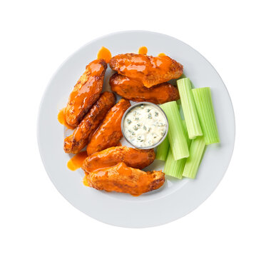 plate of Buffalo style chicken wings with celery and chunky blue cheese dressing isolated on a white background, top view.