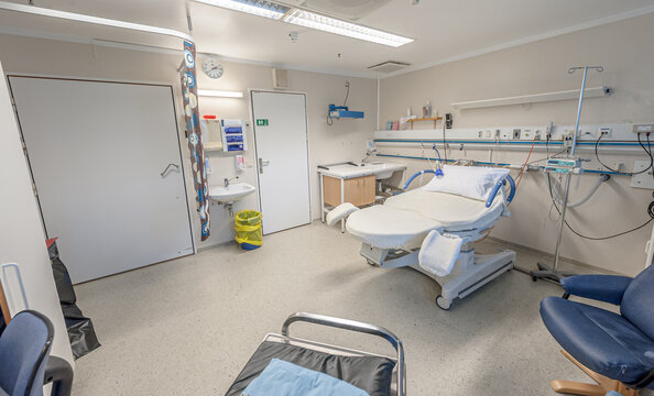 Empty hospital delivery room with medical bed and equipment.
