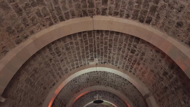 A slow camera movement looking up at an ancient stone vaulted ceiling featuring traditional masonry arches and warm ambient lighting. Ideal for historical, architectural, and cultural heritage themes.