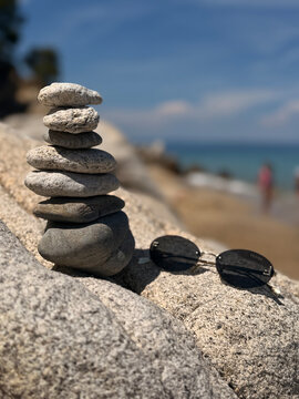 A beautiful photo of round stones against the backdrop of the sea. Glasses against the backdrop of the ocean.