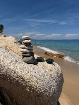 A beautiful photo of round stones against the backdrop of the sea. Glasses against the backdrop of the ocean.