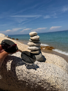 A beautiful photo of round stones against the backdrop of the sea. Glasses against the backdrop of the ocean.
