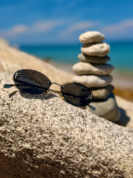 A beautiful photo of round stones against the backdrop of the sea. Glasses against the backdrop of the ocean.