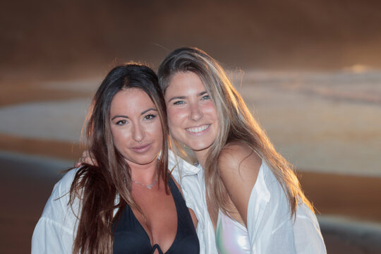 Friends embracing on beach enjoying golden hour sunset