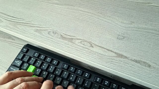  Senior person's fingers typing on keyboard tray at ergonomic computer desk with copy space
