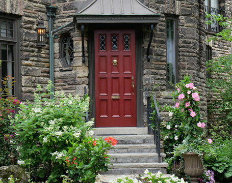 maroon colored front door of old stone house, surrounded by flowers
