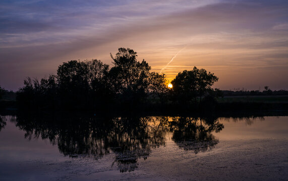 Reflection of trees at sunset on a little river.