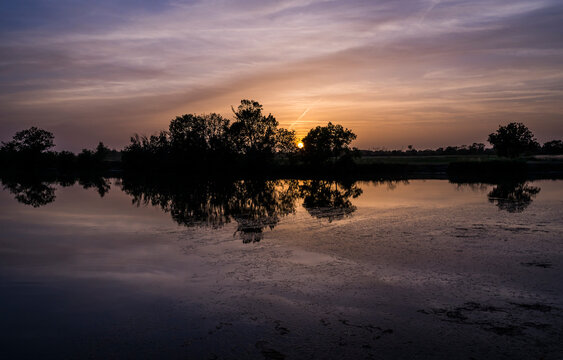 Reflection of trees at sunset on a little river.
