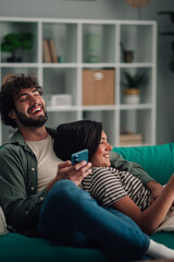 Young couple enjoying leisure time together, woman smiling and holding a smartphone while man is laughing
