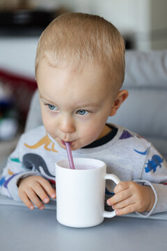 Portrait of the little boy drinking milk shake from a cup through a straw.