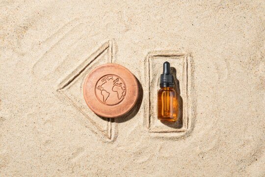 A soap bar and a bottle of oil are placed in the sand.