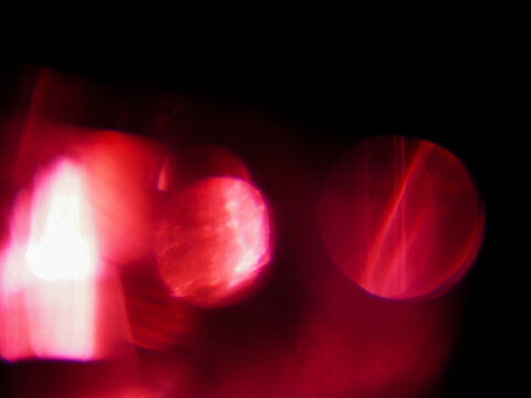 Abstract red light leaks with glowing red light streaks against dark background. Visual effect created by camera movement or light trails. Graphic background for design.
