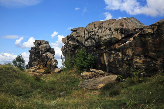 Imposante Sandsteinfelsen der Teufelsmauer im Harz. Eine markante Felsformation mit einer freistehenden Felsnadel vor blauem Sommerhimmel mit wei&szlig;en Wolken. Ideal als Naturbild.