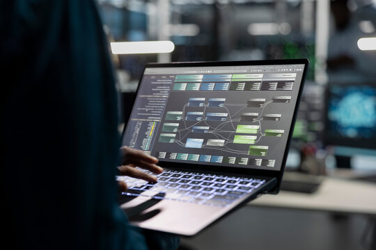 Data center engineer uses a laptop to manage machine learning workloads, working with AI technology and high performance systems.