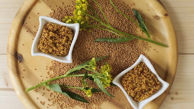 Wholegrain mustard with seeds and flowers on wooden plate