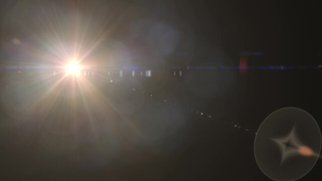 A bright sun shines over a dark landscape with prominent lens flare and starburst effects