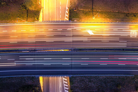 Aerial view of Tangenziale Nord di Torino highway at night with long exposure light trails from passing vehicles in Pianezza, Piemonte, Italy.