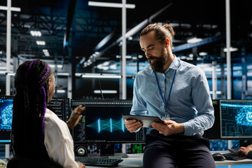 Fototapeta premium Manager and trainee tunes AI model settings on a computer workstation in a server room to improve systems.