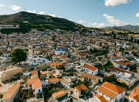 Aerial view of the historic village featuring traditional stone houses, red-tiled roofs, and a prominent church, nestled in the hills of Pano Lefkara, Larnaca, Cyprus.