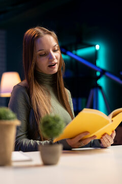 Teen content creator recording a book review video at home, discussing literature subject and author insights while influencer sharing feedback during virtual book club vlog, critic recommendations.