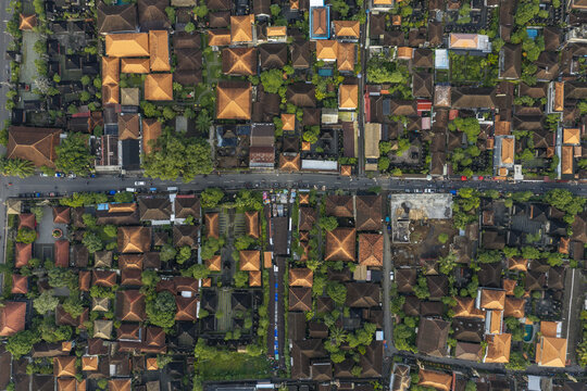 Aerial view of the town of Ubud featuring traditional Balinese architecture with terracotta rooftops, lush green trees, and narrow streets in Ubud, Bali, Indonesia.