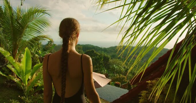 Tourist looks out over infinity pool and jungle valley during morning in Nusa Penida Bali indonesia