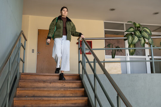 Young woman descending stairs in institutional building low angle