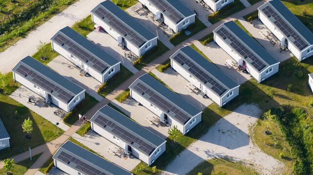 Aerial view of modern holiday homes with solar panels arranged in neat rows with paved pathways and green surroundings in Venlo, Limburg, Netherlands.