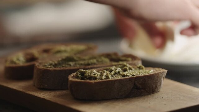Slow motion man making bruschetta with pesto and mozzarella
