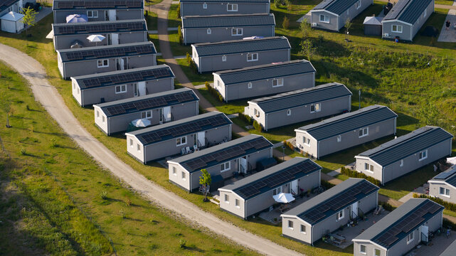 Aerial view of rows of modern grey residential units with solar panels on their roofs, situated in a green park-like setting in Venlo, Limburg, Netherlands.