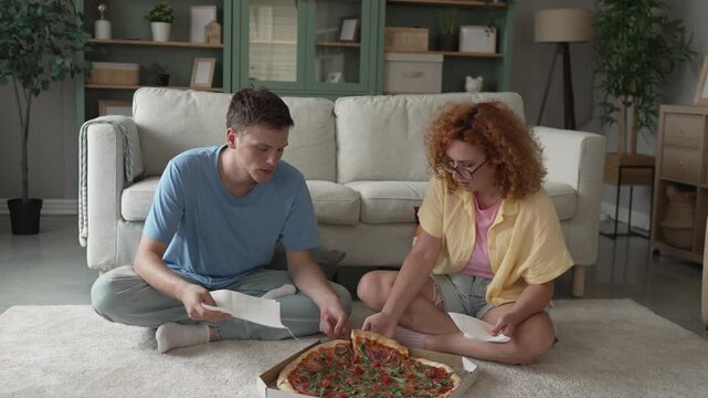 Young couple arguing and then reconciling while eating pizza