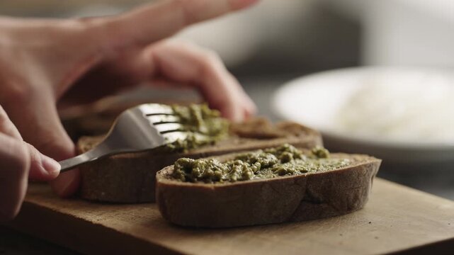 Slow motion man spread pesto sauce on bread to make sandwich