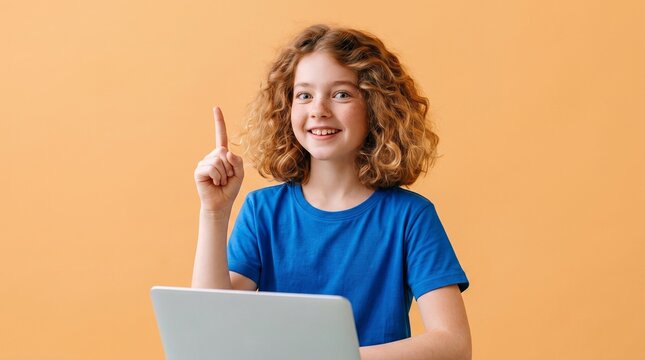 Petite &eacute;coli&egrave;re souriante avec un ordinateur portable pointant le doigt vers le haut pour une id&eacute;e. Concept d'&eacute;ducation en ligne, cours pour enfants et &eacute;cole &agrave; la maison sur fond orange.