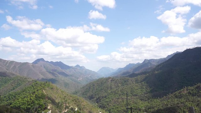 A breathtaking panoramic view of the mountain valleys of El Salto, near Monterrey, Nuevo Le&oacute;n, Mexico. Rolling green hills, rugged mountain peaks, and scattered white clouds under a bright blue sky