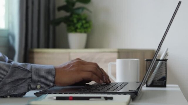 Close up of hands typing on laptop with coffee cup in modern workspace, representing remote work, productivity, focus, digital lifestyle, professional workflow and comfortable home office environment.