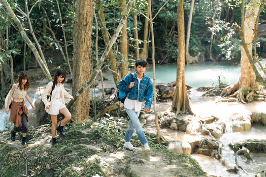 Group of Young Asian man and woman friends hiking through tropical forest trail together enjoying eco tourism adventure outdoor travel active lifestyle nature therapy on summer holiday vacation.