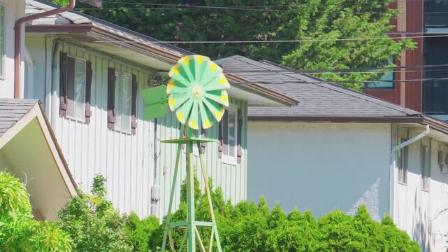 Medium shot of a decorative green and yellow metal miniature weather vane windmill.