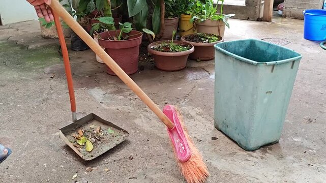 Person sweeping backyard collecting dry leaves and organic tree waste
