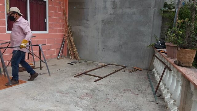 Young man carrying metal workbenches in workshop outdoor area