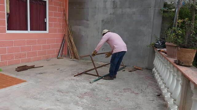 Welder aligning and positioning square steel profile base structure on floor