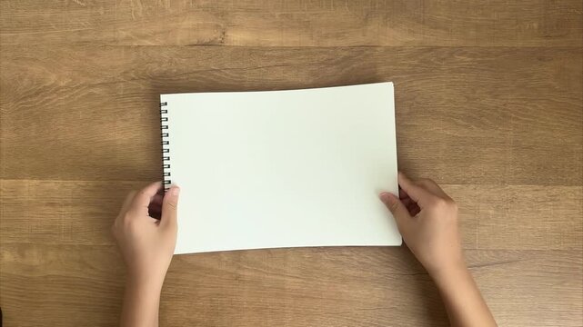Child Places a White Sketchbook on a Table and Parent's Hands Straighten It, 4K