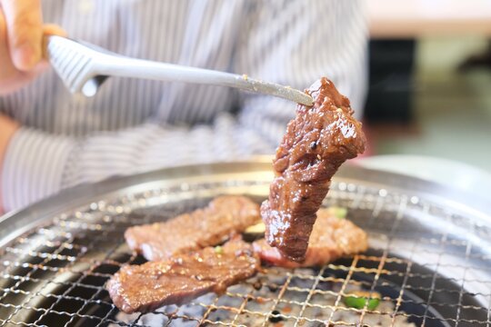 トングで持ち上げた焼き立ての牛ハラミの肉