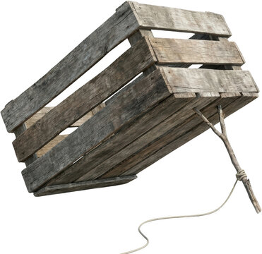 An aged wooden crate with weathered planks and a rope tied to a small branch is angled downwards suggesting rustic storage or transport timber construction vintage old container