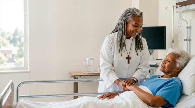 Hospital chaplain comforting elderly patient. African American religious woman holding hands with senior woman in hospital bed. Spiritual care and support in healthcare. Copy space for text